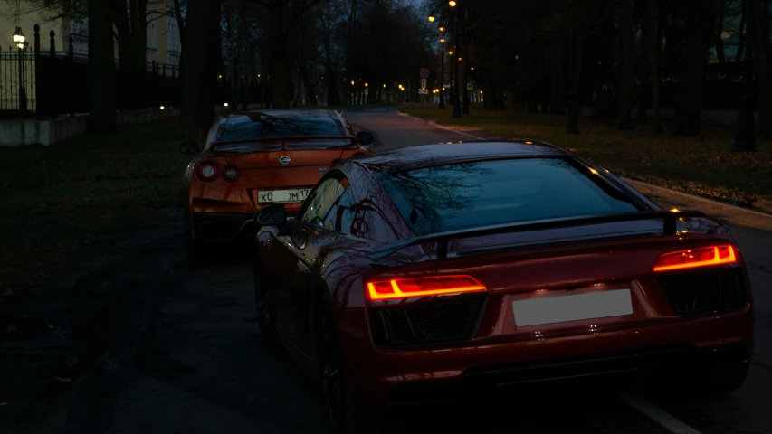 a night time view of two sports cars parked in a parking lot