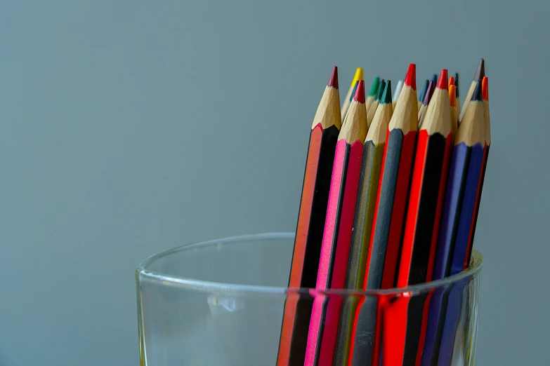 many colored pencils in a clear glass