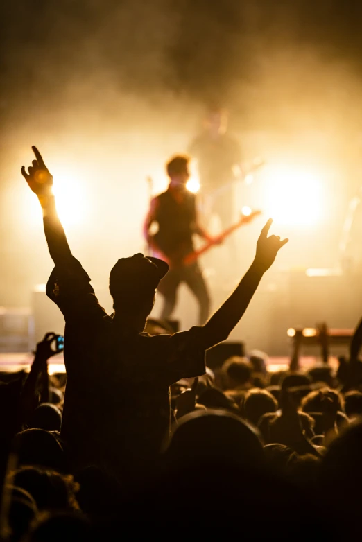 someone raising their arms in front of the crowd