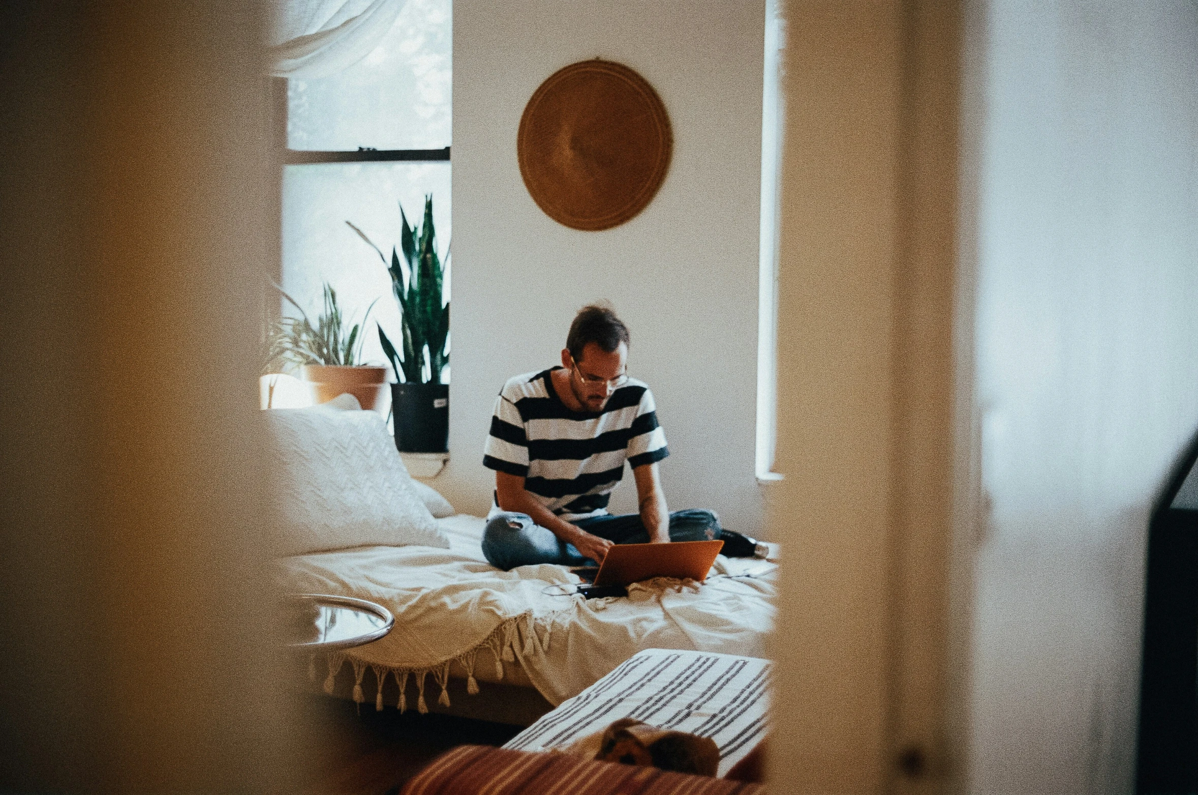 man sitting on a bed with a laptop and other items nearby