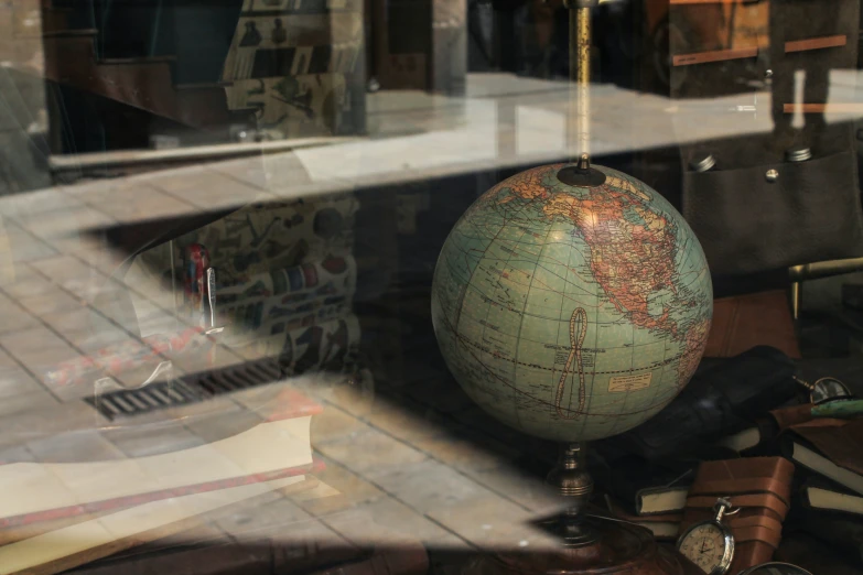 the inside view of a glass case, with an old globe and other vintage items