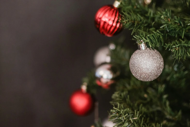 christmas ornaments hanging on the evergreen nch with dark background