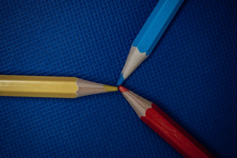 two pencils laying on a blue surface with their end together