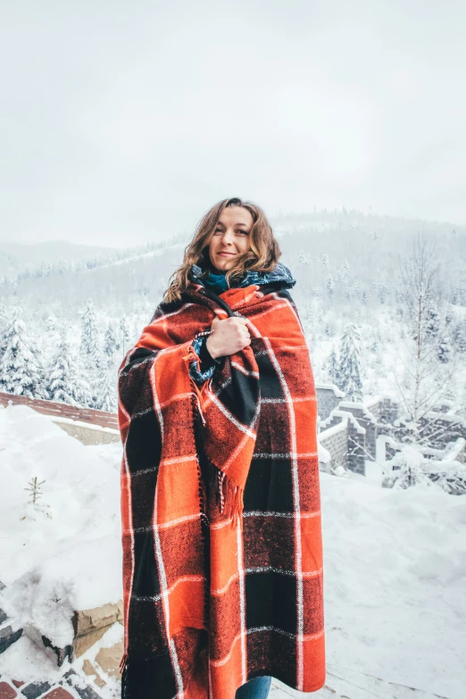 a woman stands under a blanket with a mountain in the background