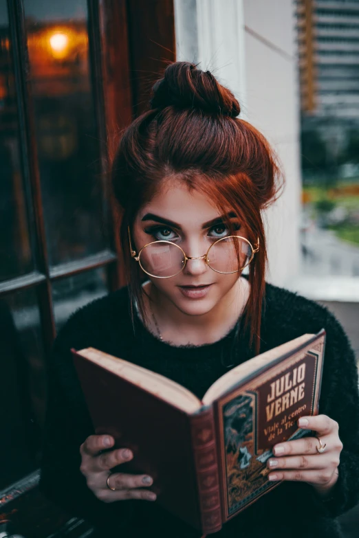 a woman with red hair is reading a book