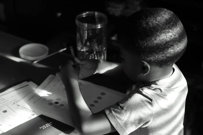 a small child at a desk writing on a piece of paper