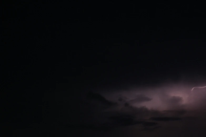 a dark sky with a plane flying over it and lightning coming from the right side