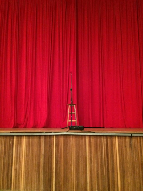 a small tower with a light at the top in front of red curtains