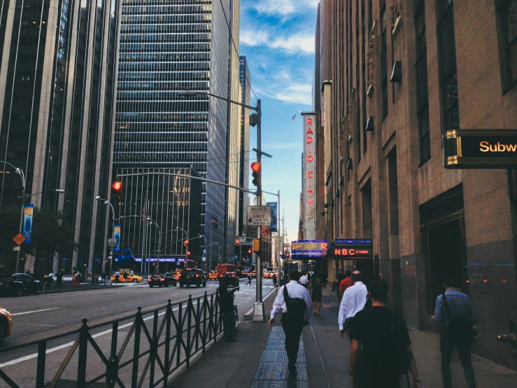 some people are walking on a sidewalk beside buildings