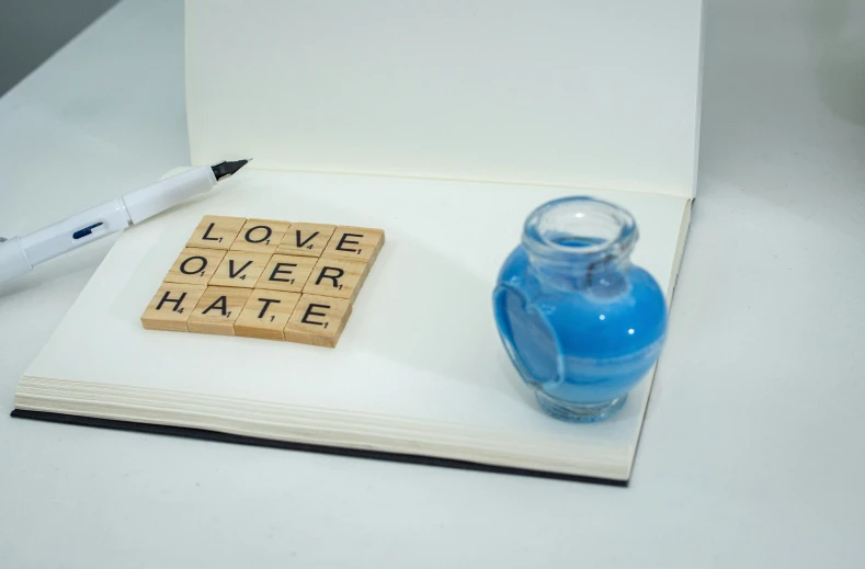 a note book with scrabbles, a pen and a bottle on top
