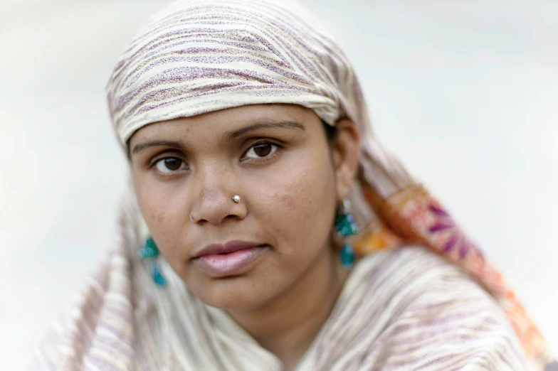 a young woman in a colorful head scarf with earrings on