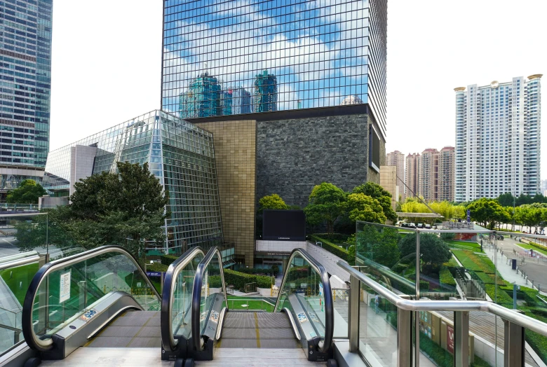 two escalators in the city area with buildings reflected in glass windows