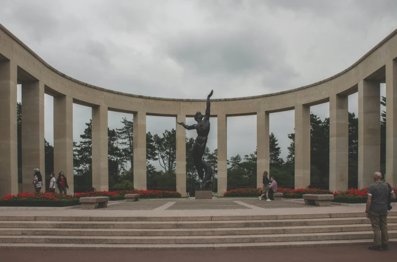 several people walk in front of a large statue