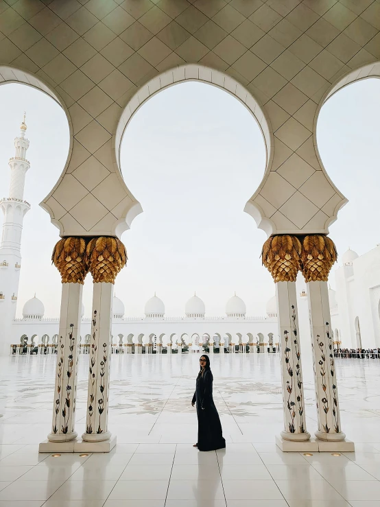 a woman walking through a white palace with arches