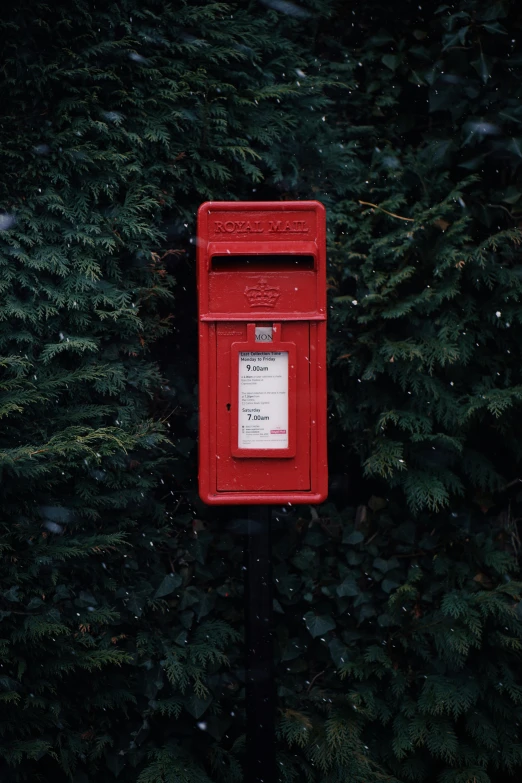 an old fashioned red mail box stands in front of some trees