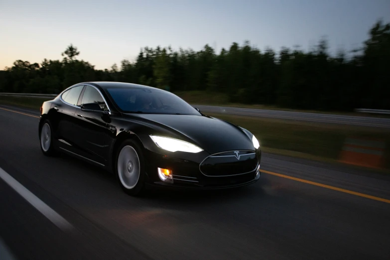 the black tesla is driving down the road