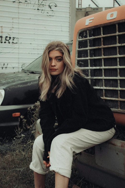 woman sitting on the bumper of an old dump truck