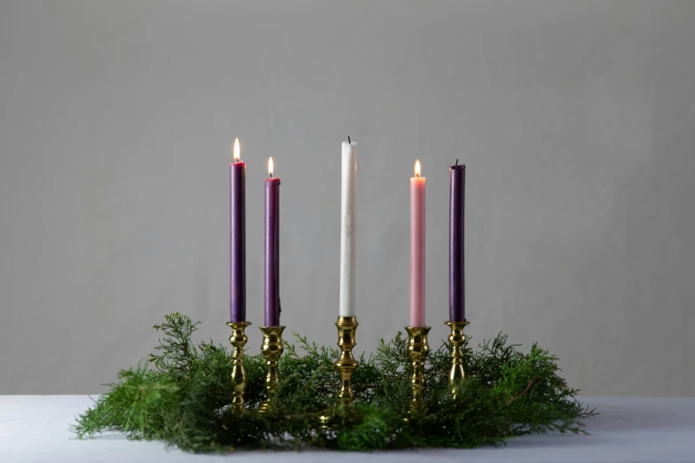 three candles stand on a christmas wreath