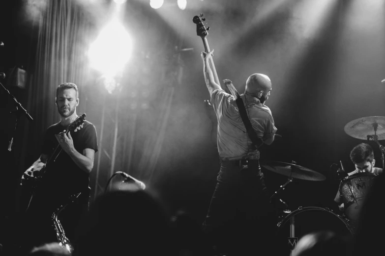 two men in the middle of a band holding up their arms