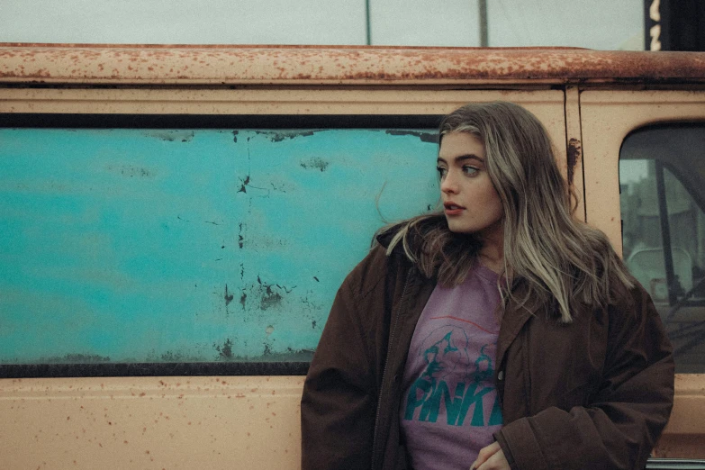 a woman standing against a rusted bus