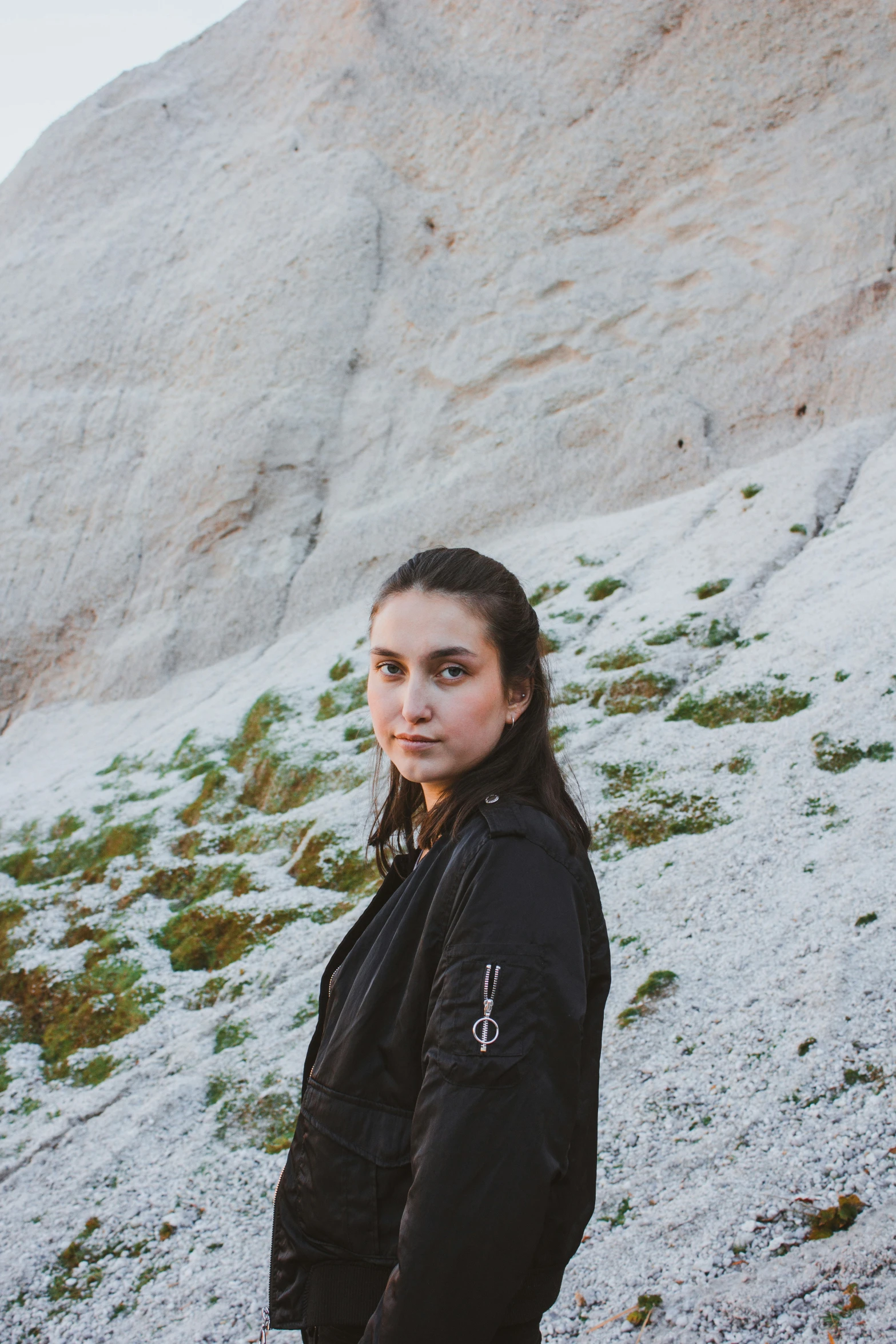 a young woman is standing near a large snow covered hill