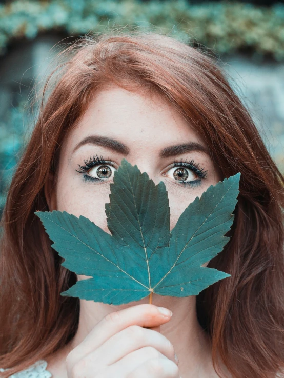 a girl has an orange and green leaf over her face