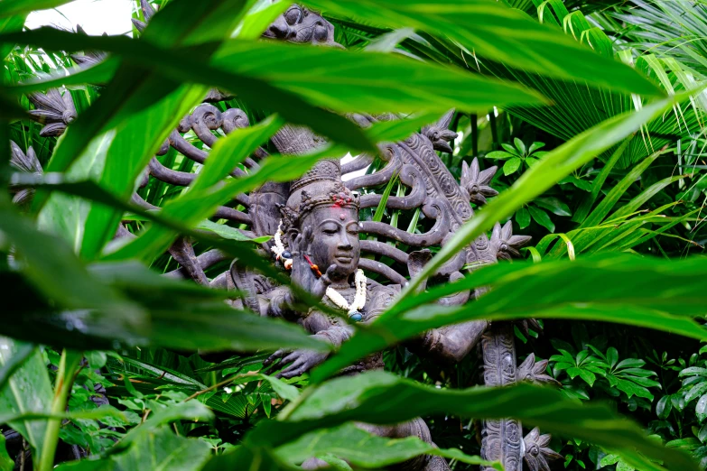 an artful sculpture of a gorilla looks through the bushes