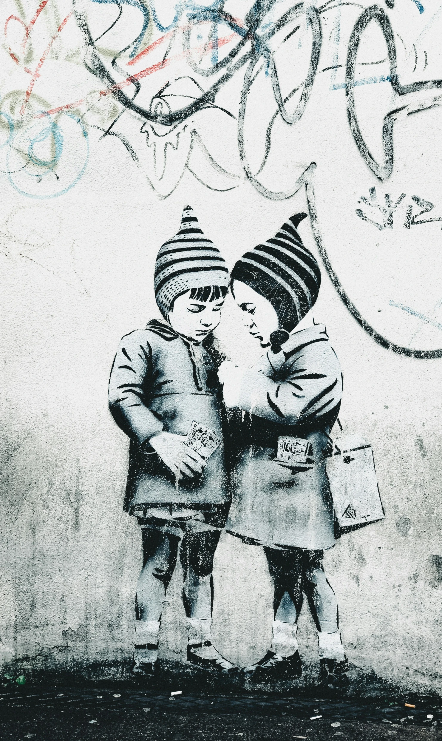 two children in hats stand near a graffiti wall