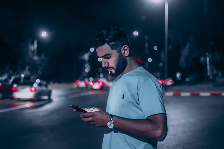 man standing on a street at night with mobile phone