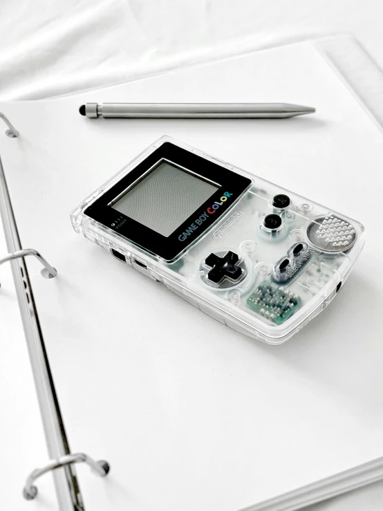 this is a nintendo gameboy sitting on a table next to a pen and book