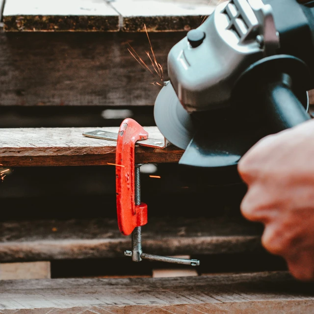 a man uses a small corded drill to nail a piece of wood