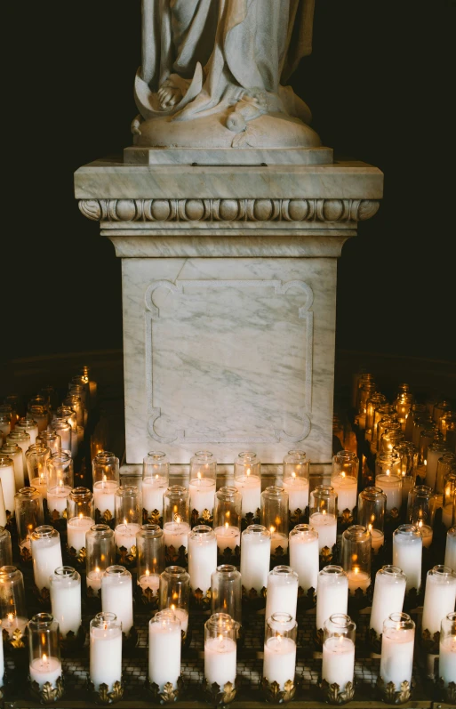 many lit candles near a statue at night