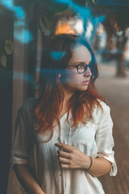 a young woman wearing glasses and leaning against a tree