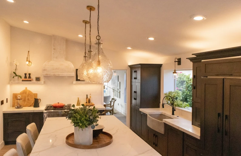 a large kitchen with dark cabinets, an island counter and a long countertop