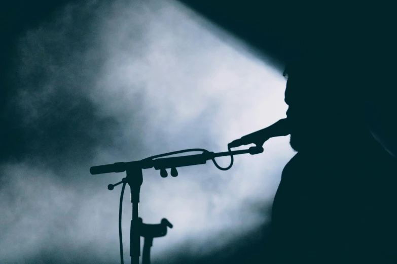 a person with microphone on stage in front of dark lighting