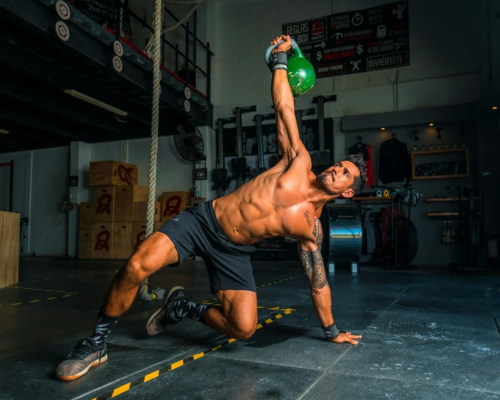 a man with one leg up and an empty bottle in his hand doing h ups