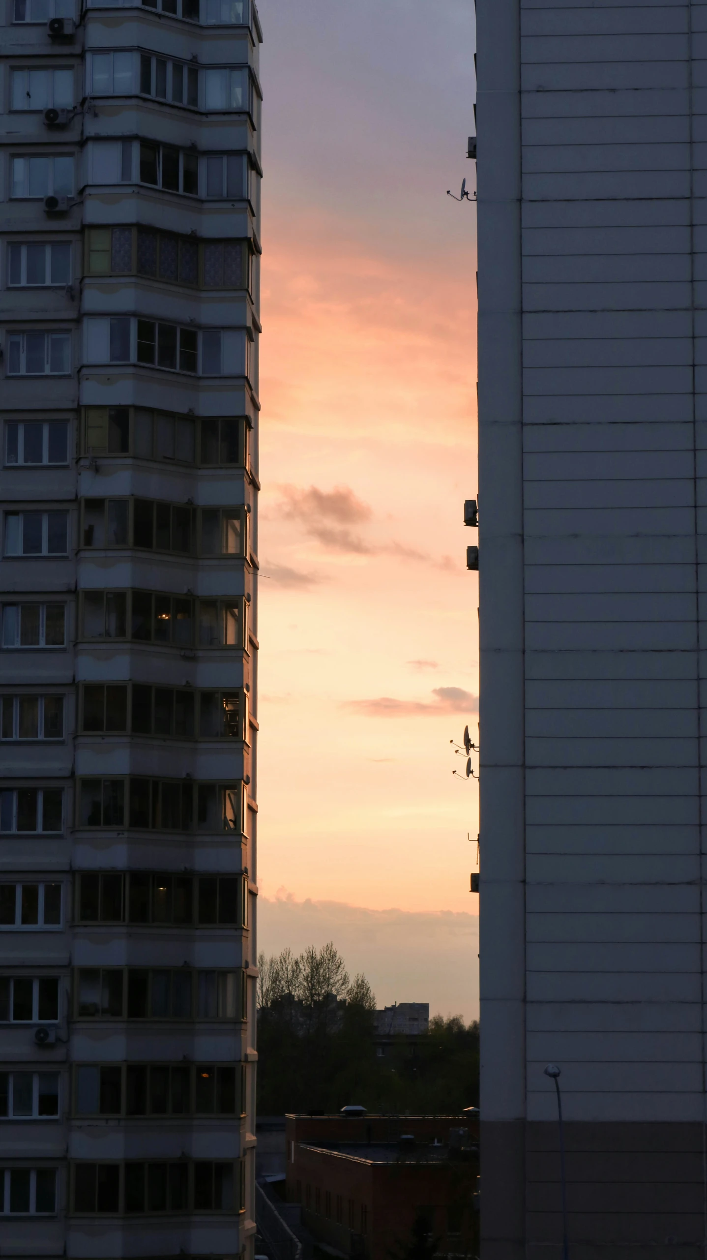 two tall buildings in front of a sunset