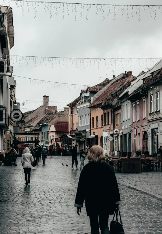 people are walking down a brick sidewalk near buildings