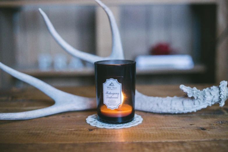 a candle sitting on the ground next to white reindeer antlers