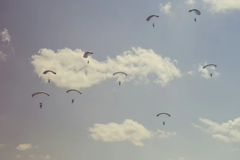 people are paragliding under a blue cloudy sky