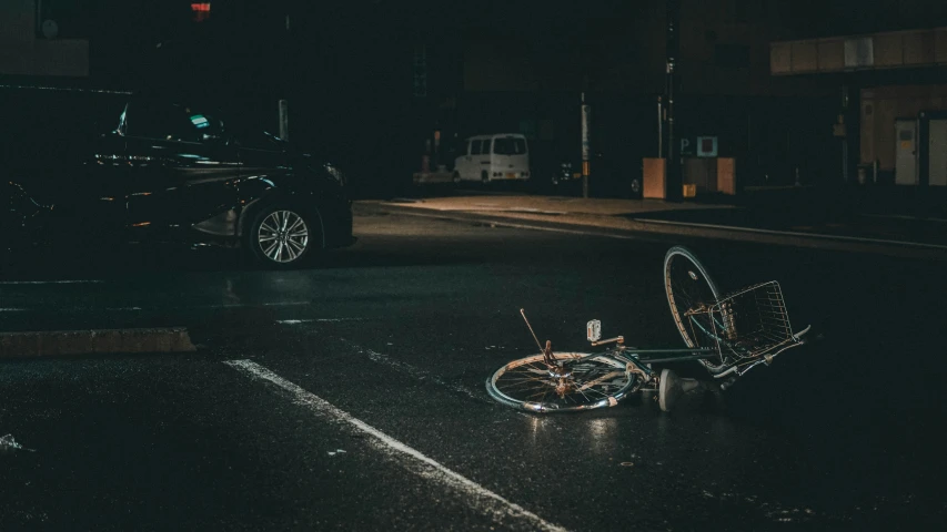 a bicycle lying on a city street next to a black truck