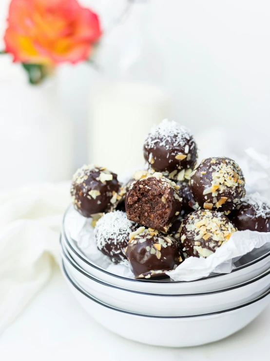 a white bowl holding several chocolate covered deserts