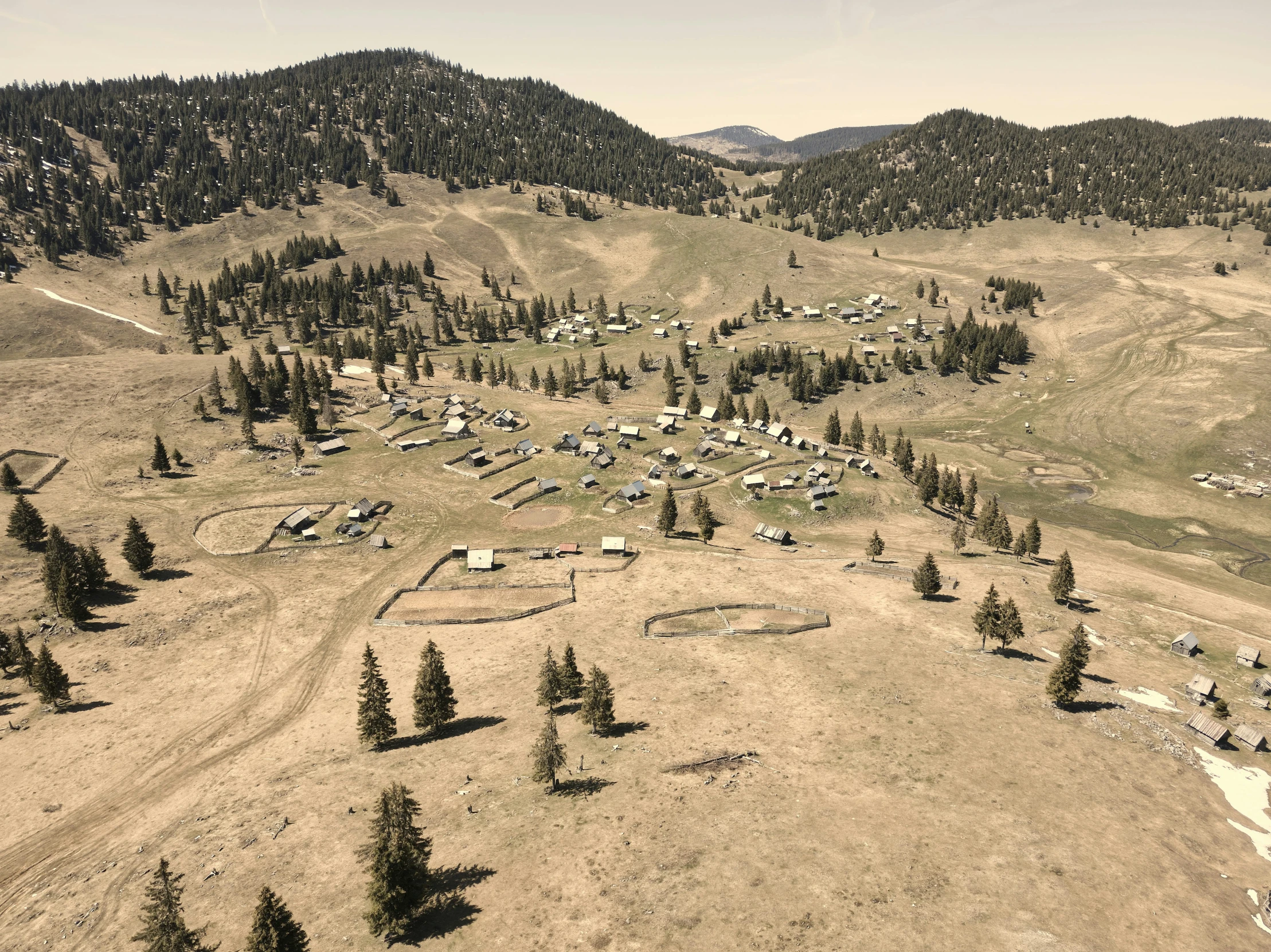 an aerial view of some trees and cabins in the mountains