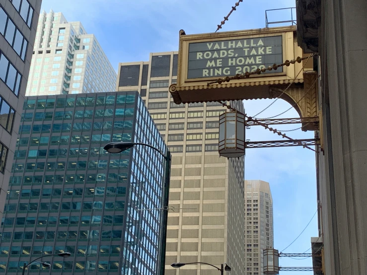 an overhead message sign in between skyscrs with buildings behind it