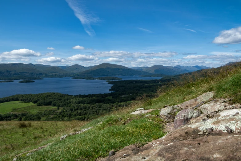 a large body of water next to a grassy hillside