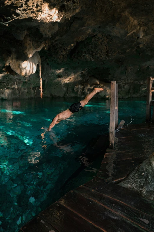 a man is floating in the pool in a cave