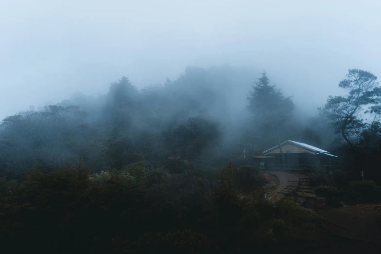 a small house with fog on top of a hill