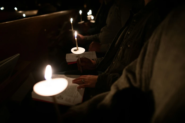 people are reading books and lighting candles in a church