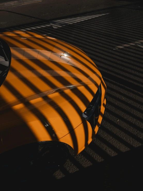 shadows are cast onto a parked orange car