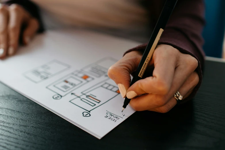 person writing on paper next to a pen